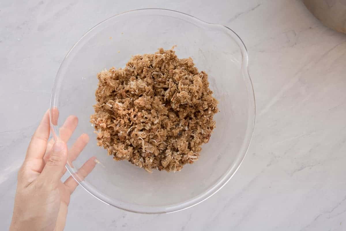The coconut pecan topping is mixed in a clear glass mixing bowl.
