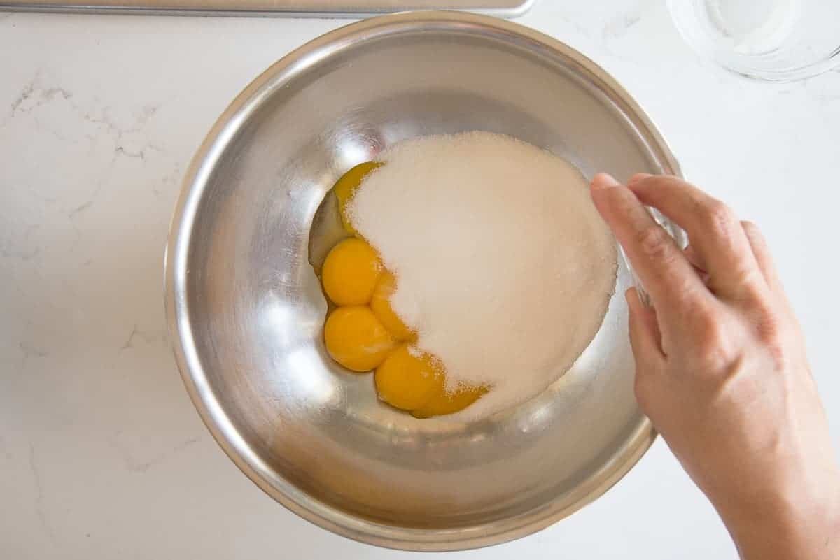 The eggs, sugar, and salt are added to a silver mixing bowl.