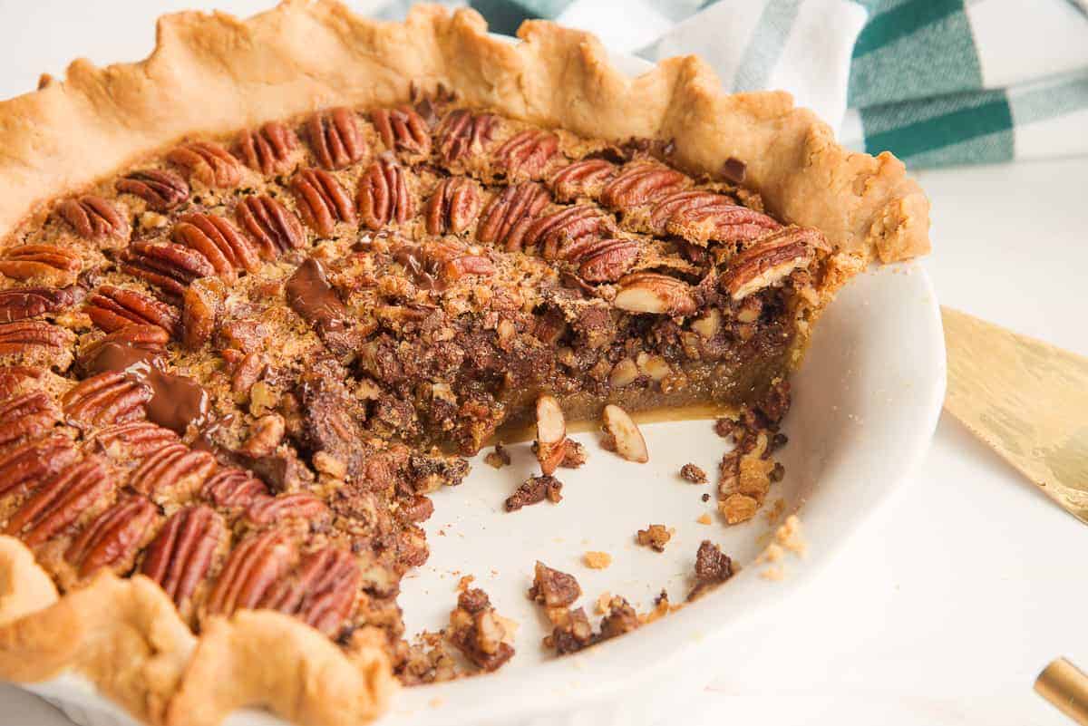Maple Bourbon Pecan Pie with Chocolate Chunks in a white ceramic pie plate cut to show the interior
