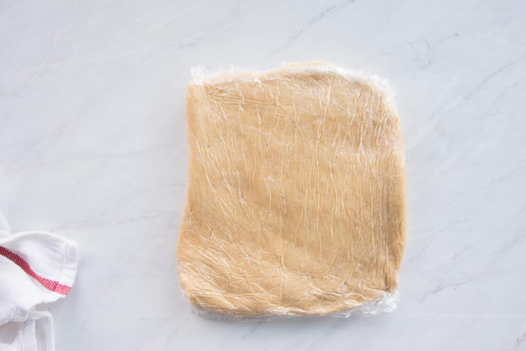 The dough is formed into a rectangle and wrapped in plastic before going into the fridge to chill.