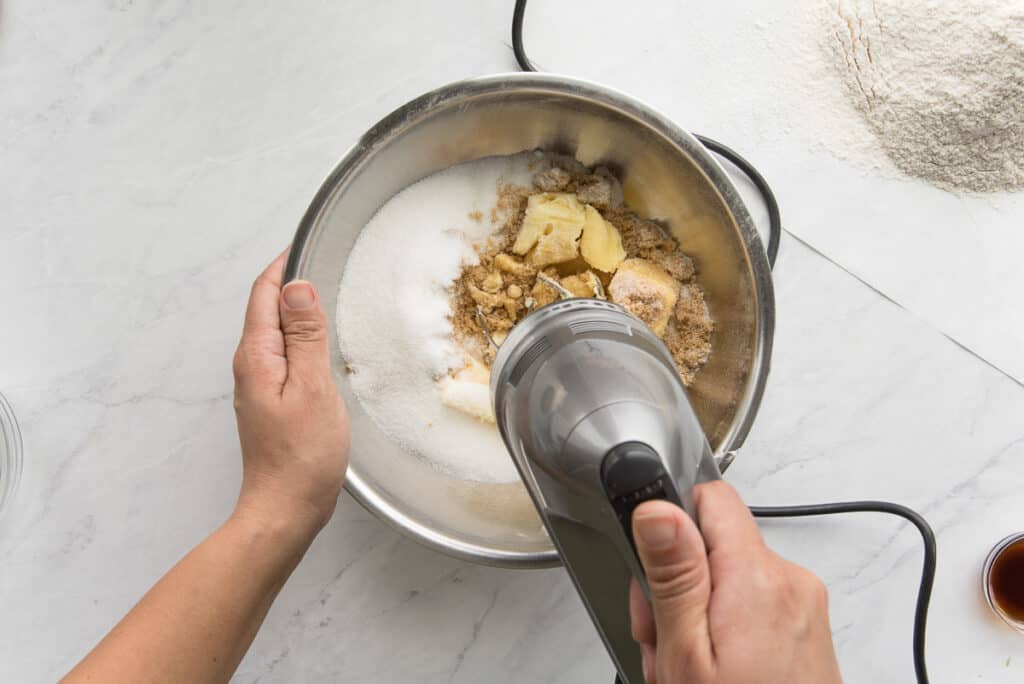 The butter and sugar are blended together in a sliver bowl with an electric hand mixer.