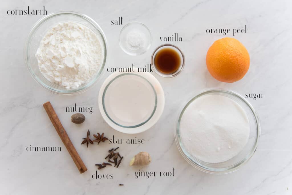 Ingredients to make Tembleque: cornstarch, salt, vanilla, orange peel, sugar, coconut milk. cinnamon stick, nutmeg, star anise, cloves, and ginger root.