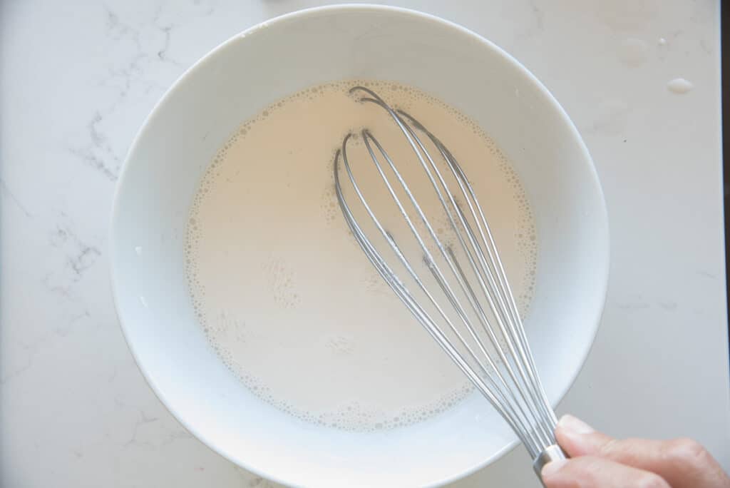 A whisk is used to mix the cornstarch and coconut milk together.