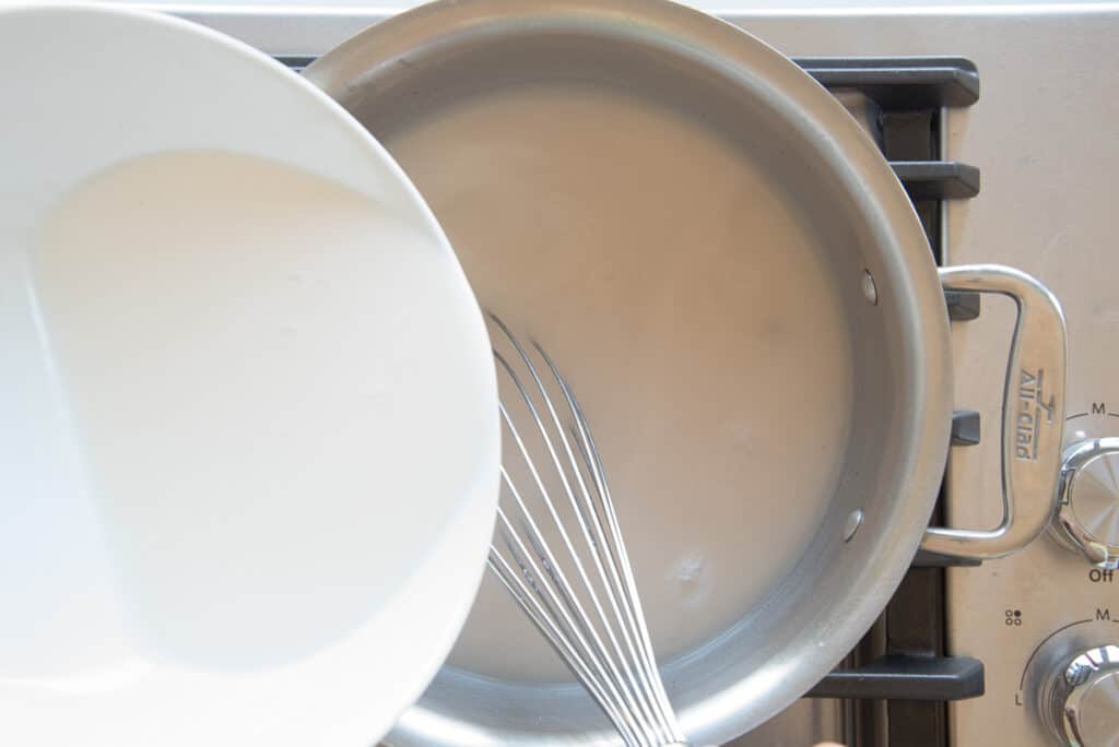 The cornstarch slurry is whisked into the pot of coconut milk