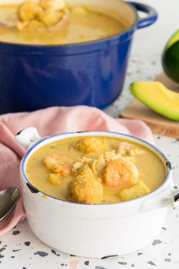 Preview image of a white bowl of Caldo Santo on a terrazza surface. A blue pot of caldo santo is in the left background.