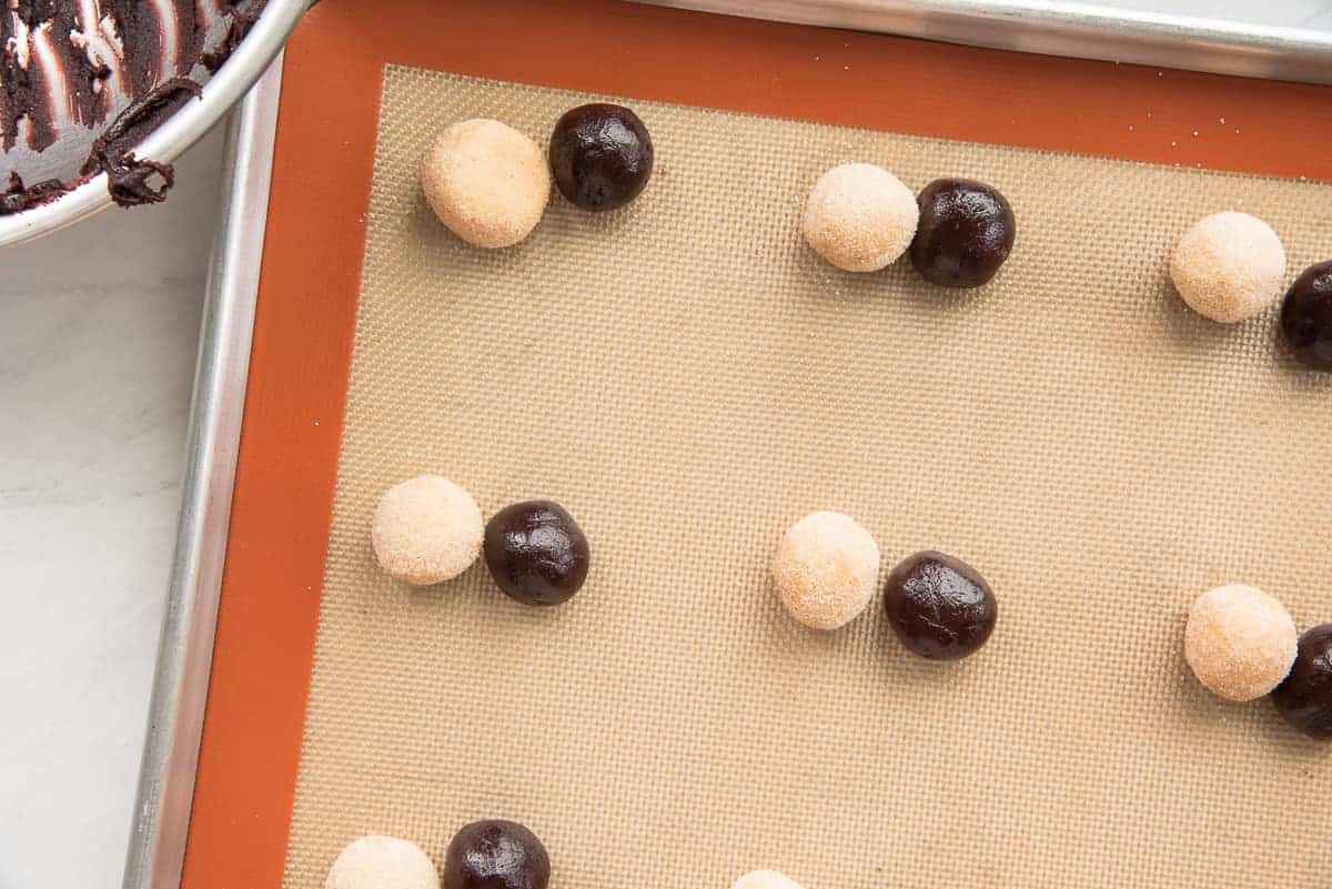 The two dough balls sit next to each other on a silpat silicone baking mat.