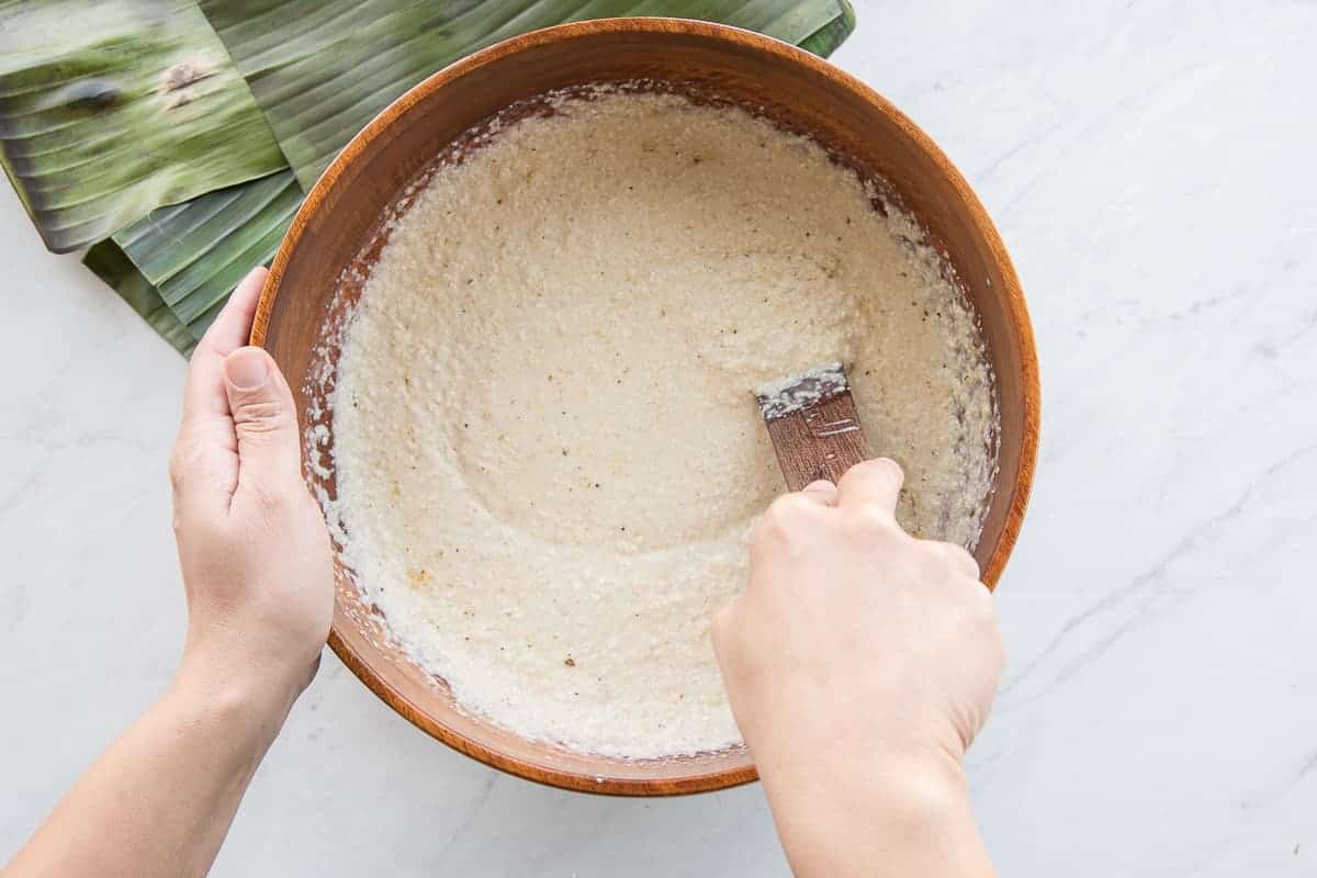 The coconut grits mixture is stirred together in a wooden mixing bowl.