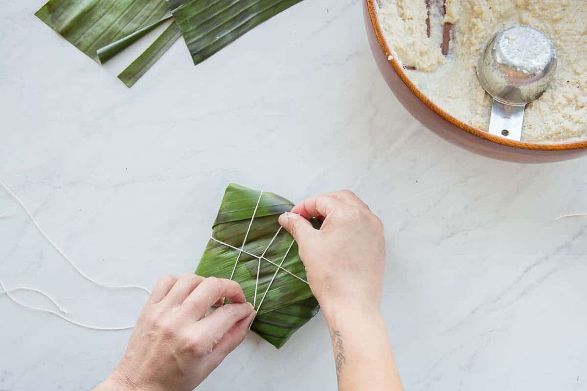 The coconut grits mixture is wrapped in banana leaves.