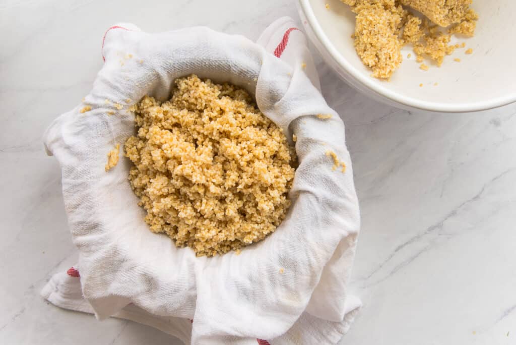 Bulgur is in a kitchen towel before being squeezed to remove excess water.