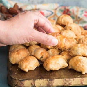 Preview image: hand lifts one of the Goat Cheese Stuffed-Dates in Puff Pastry from the pile