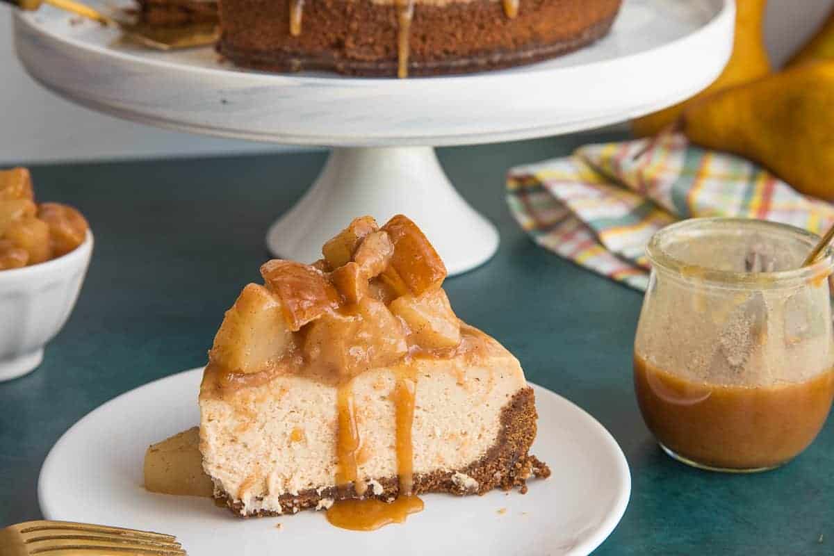 A slice of Cinnamon Cheesecake with Spiced Pear Topping next to a jar of Spiced Toffee Sauce