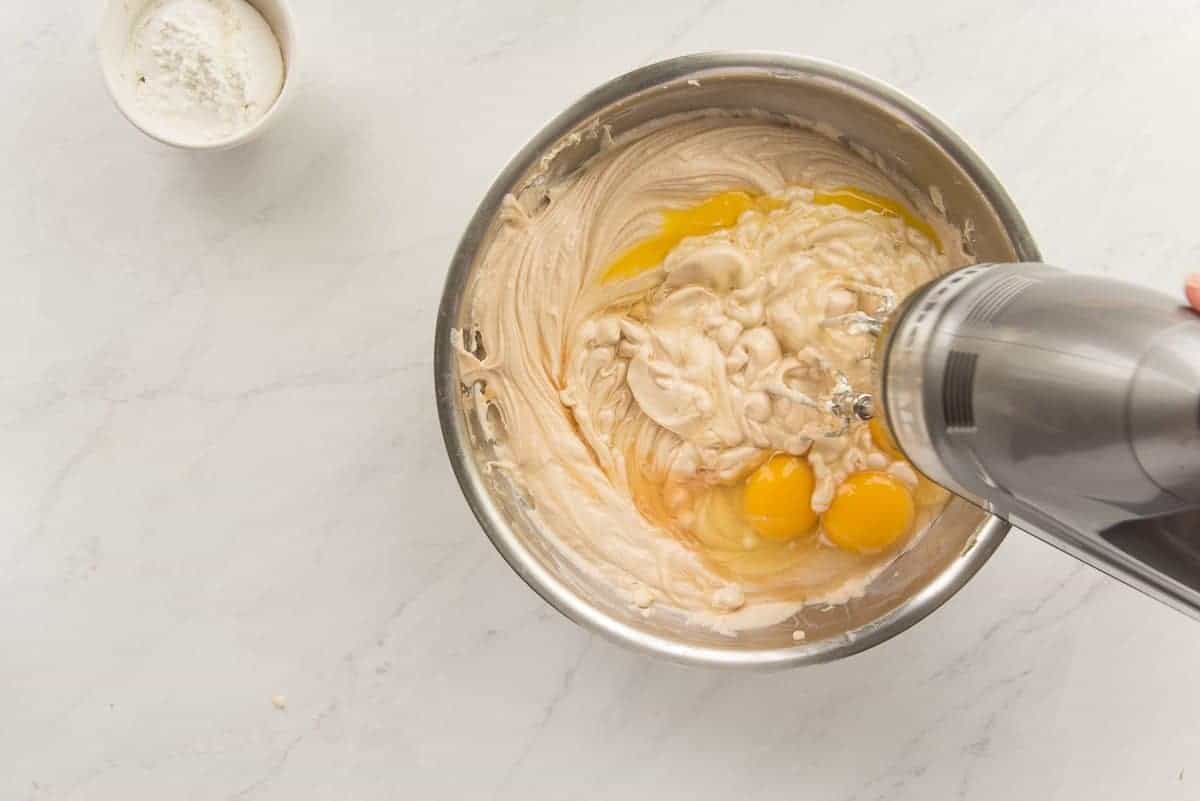 Eggs are blended into the rest of the ingredients in a metal mixing bowl.