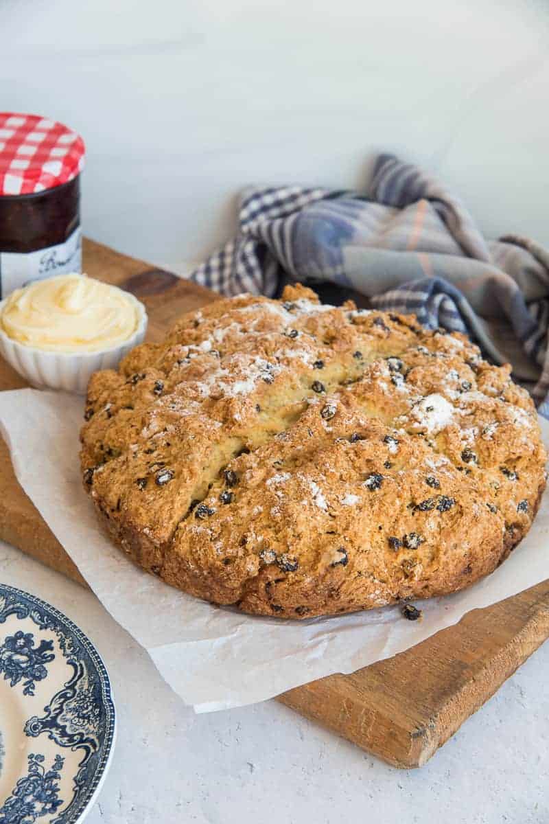 Irish Soda Bread on a white piece of parchment on a wooden board.