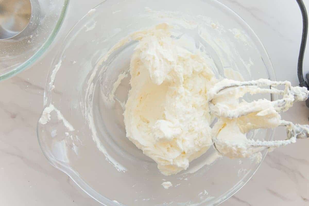 The butter and sugar mixture is creamed together in a clear, glass mixing bowl.