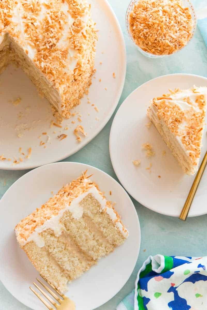 Two slices of Toasted Coconut Cake on white plates.