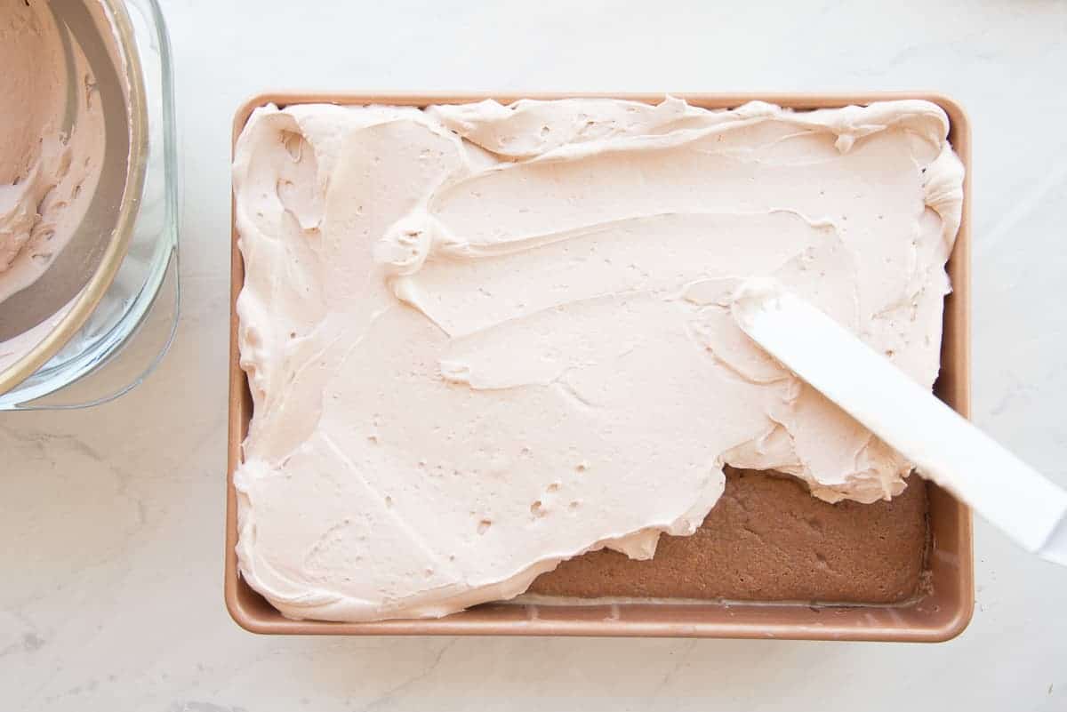 An offset spatula swirls chocolate whipped cream over the dessert.