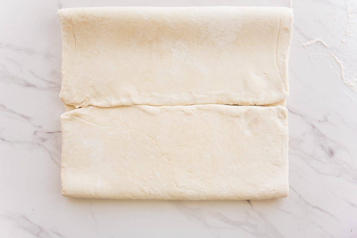 The two ends of the dough are folded into the center of the rectangle of dough.