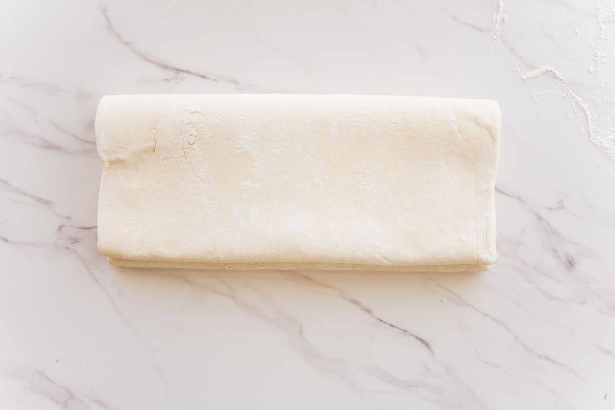 The dough is folded like a book on a white surface.