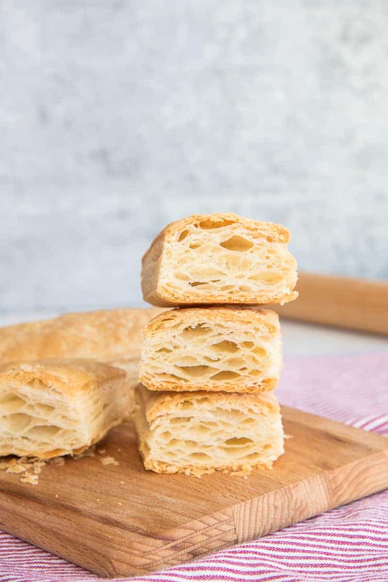 Portrait of a stack of Puff Pastry on a wooden board cut open to reveal interior.
