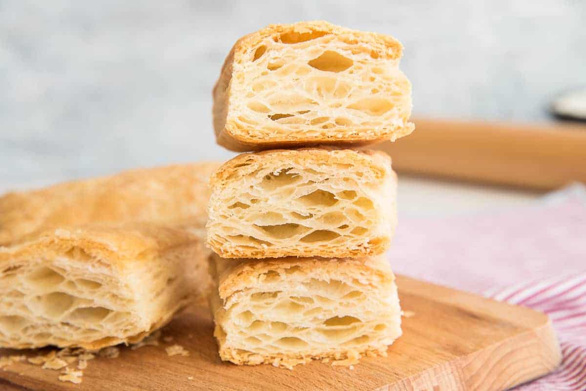 Puff Pastry cut open to reveal the flaky layers inside on a wooden cutting board.