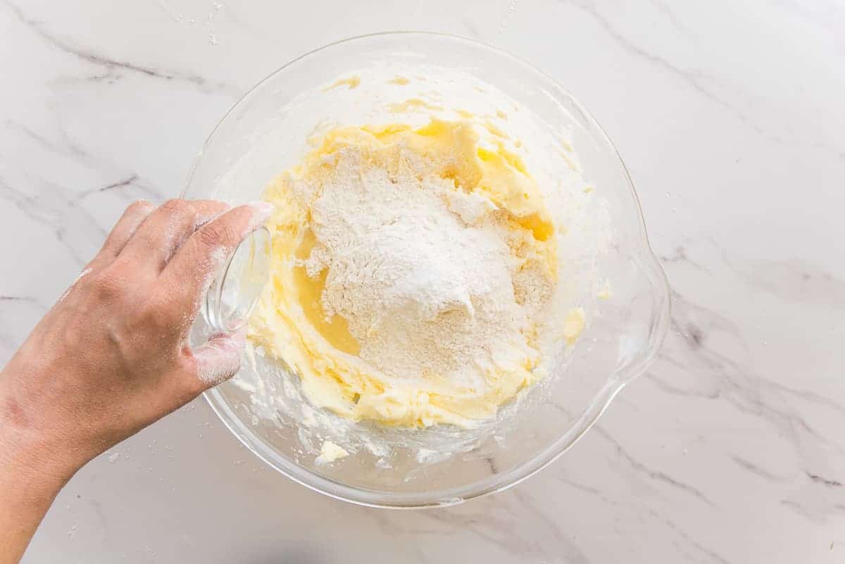 Flour, salt, and lemon juice are added to the butter paste in a clear mixing bowl.