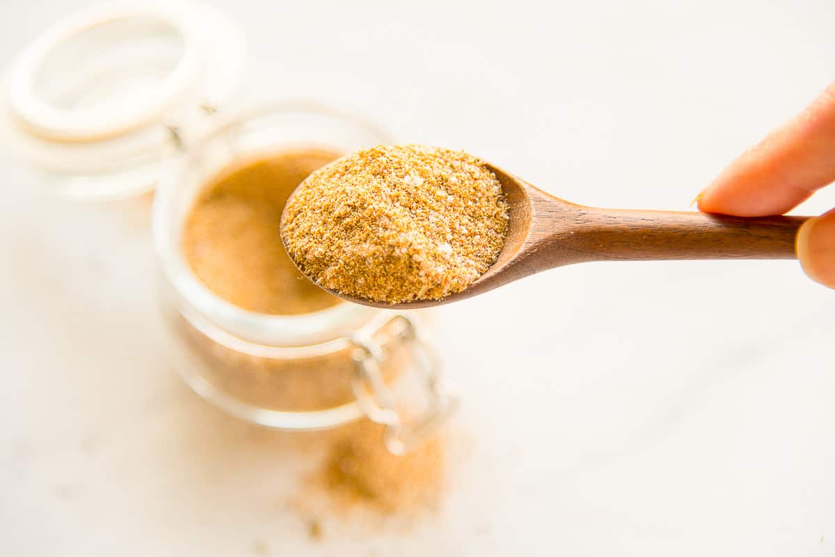 A hand holds a spoon with the Chicken Seasoning Blend on it.