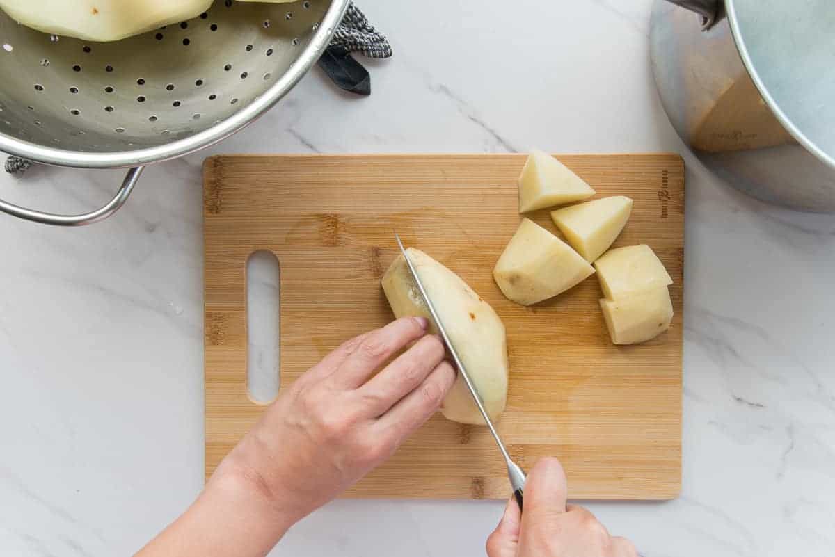 The spuds are cut on a wooden cutting board.