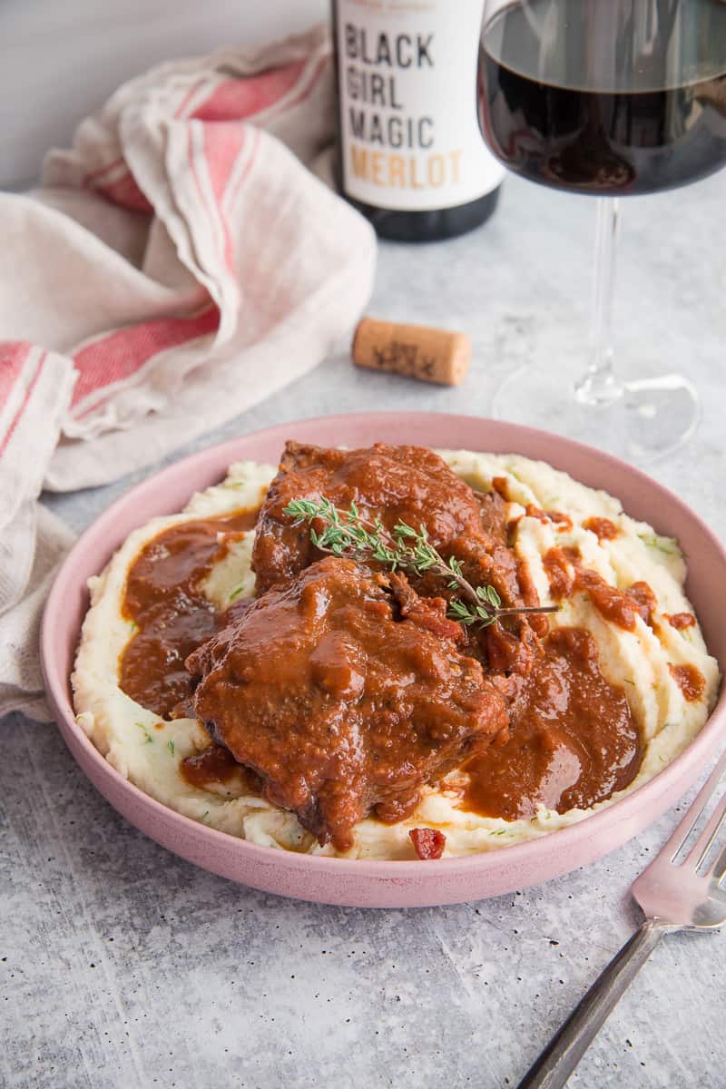 The Merlot Braised Short Ribs in a pink bowl over mashed potatoes.