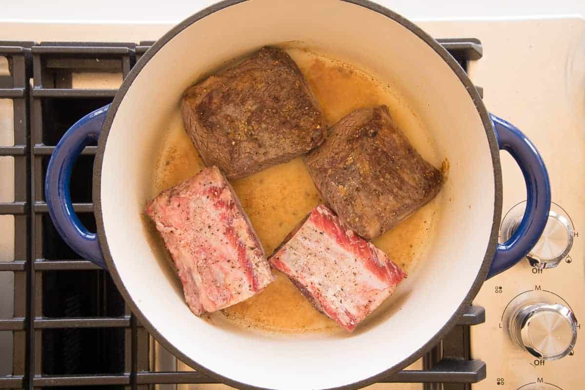 The beef is seared in a Dutch oven.