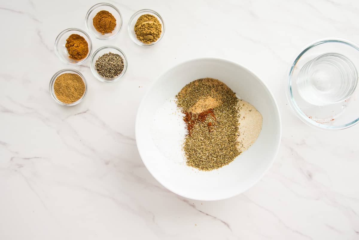 The herbs and aromatics are added to a white mixing bowl.