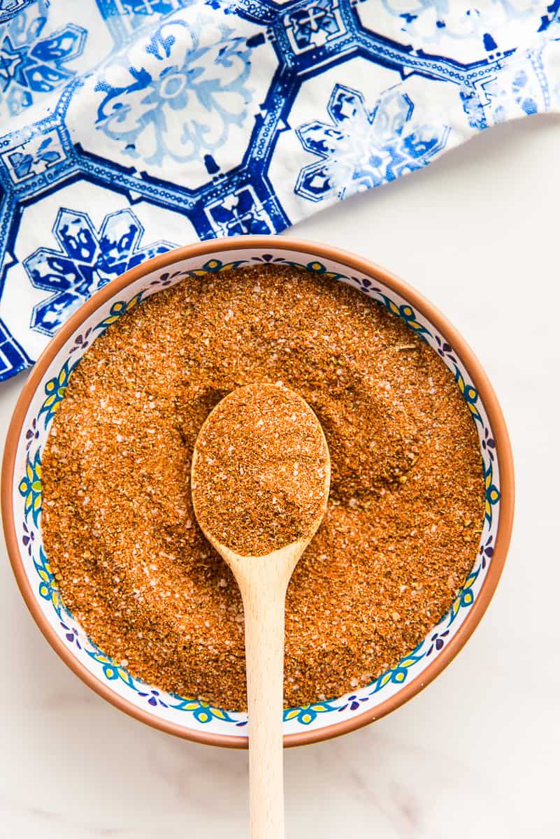 A spoon has some of the Mexican Four Chile Spice Blend on it and lies on top of the rest of the spice blend in a bowl.