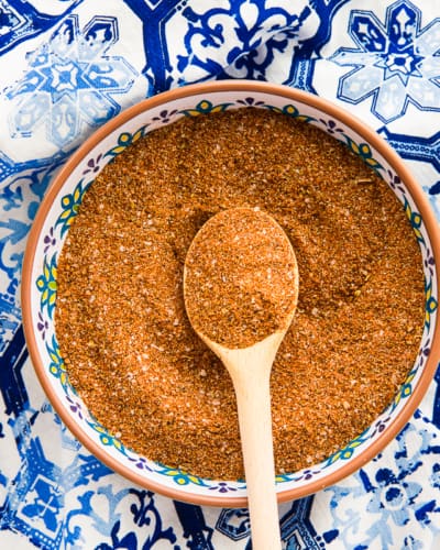 A bowl filled with the Mexican Four Chile Spice Blend on a blue mosaic surface.