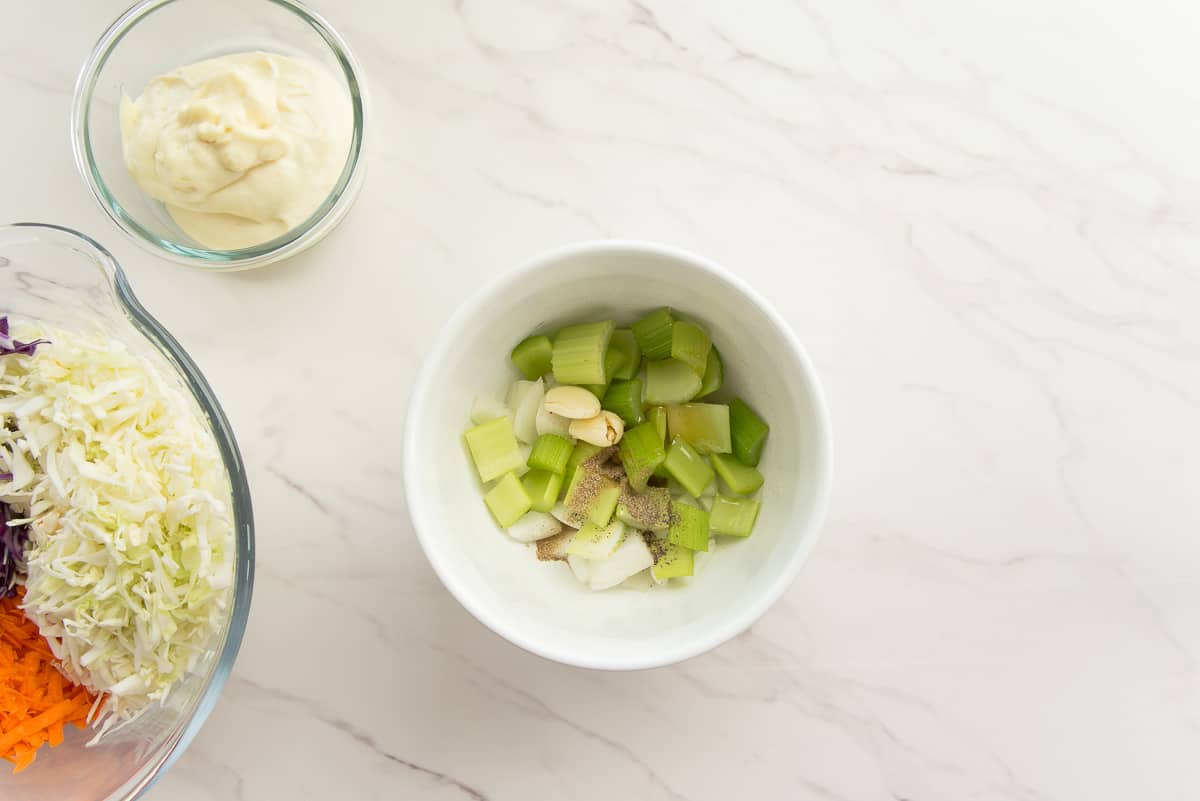 The celery, onion, garlic, and spices are combined in a white mixing bowl.