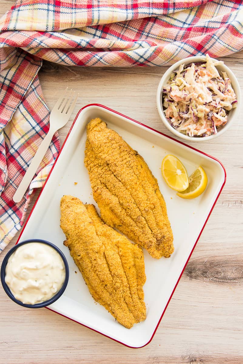 Two Air Fried Southern Catfish filets on a tray next to a bowl of coleslaw.