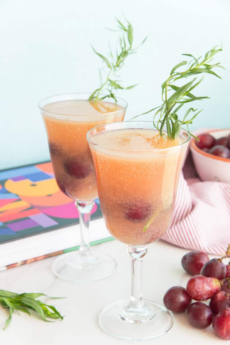 Grape Tarragon Gin Spritzers in goblets garnished with tarragon sprigs