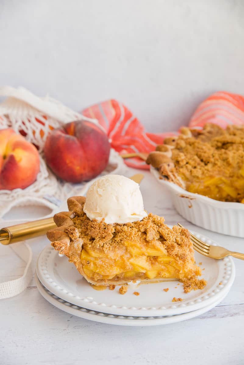 Portrait of a slice of Peach Pie with Cornmeal Crumble Topping topped with vanilla frozen custard.