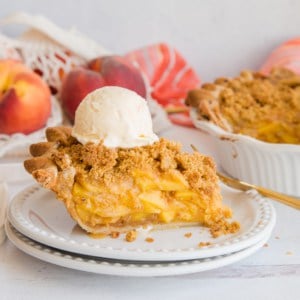 A slice of Peach Pie with Cornmeal Crumble Topping topped with vanilla frozen custard on a white plate.