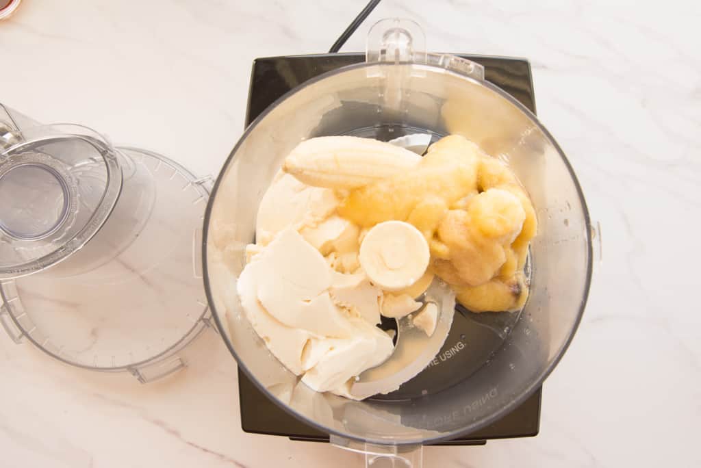 Silken tofu and bananas are added to a food processor.