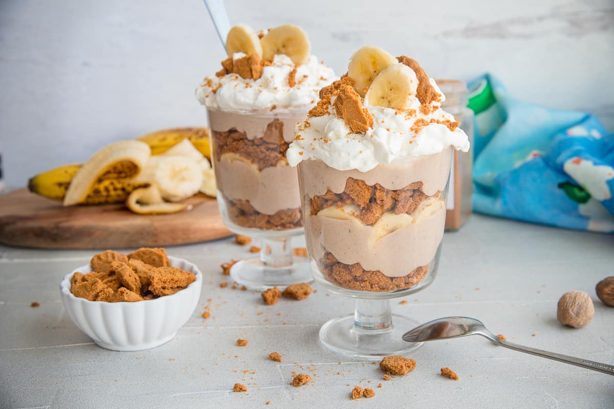 Two goblets of Vegan Banana Pudding garnished with whipped topping and crushed cookies and banana slices.