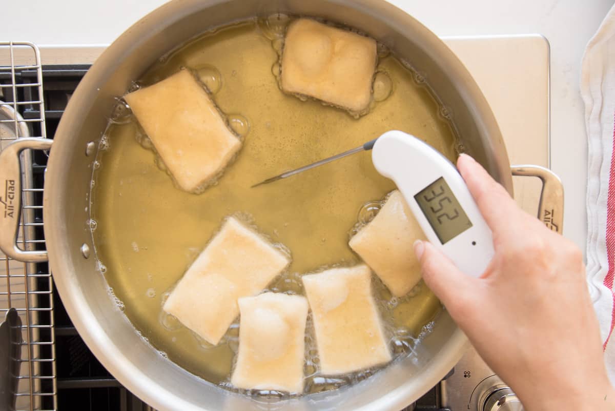 A thermometer measures the oil's temperature reading 352°F while the Beignets fry.