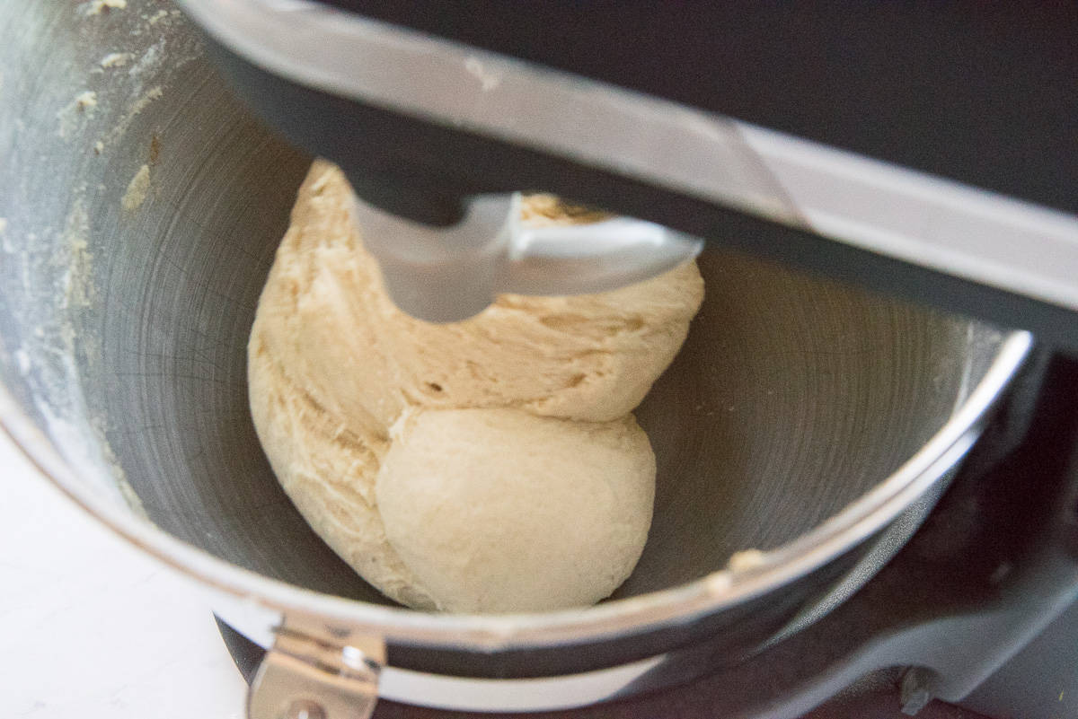 The dough is mixed with a dough hook in the bowl of a stand mixer.