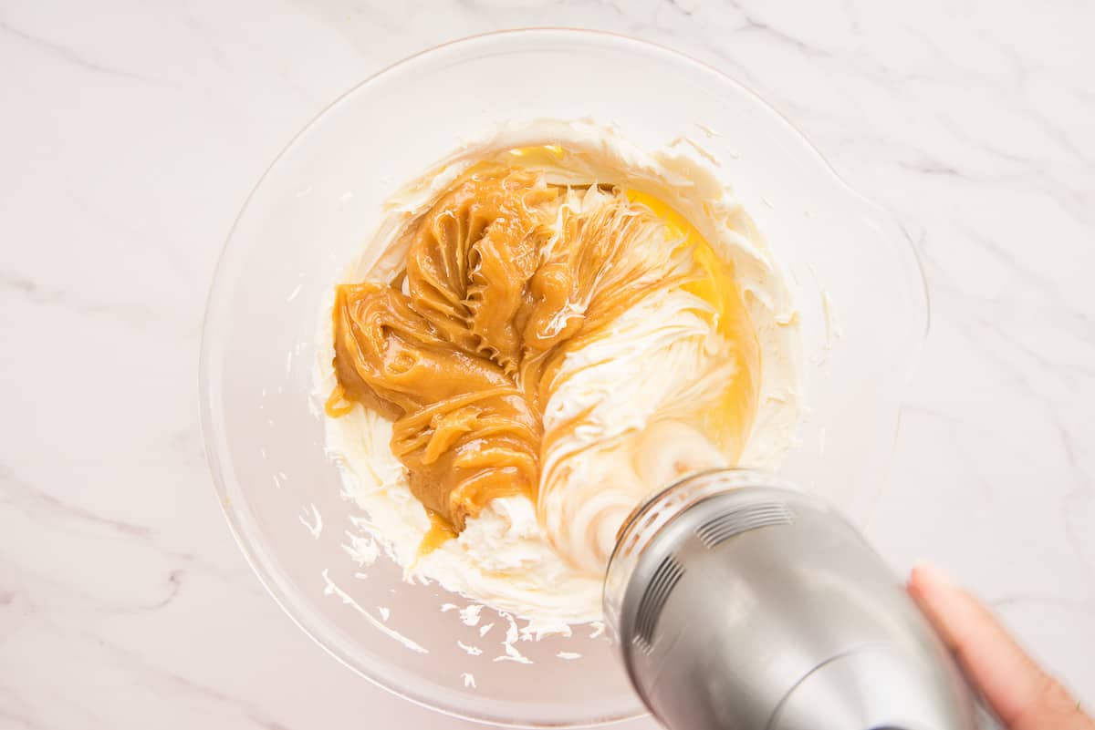 An electric mixture blends together the sabayon and mascarpone cheese in a clear mixing bowl.