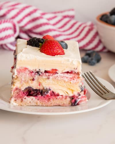 A piece of Berry Tiramisu on a white plate with a silver fork propped on the right side of the plate.
