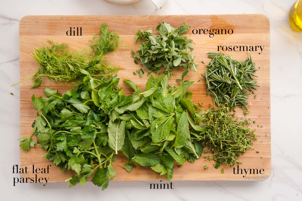 The herbs on a wooden cutting board.