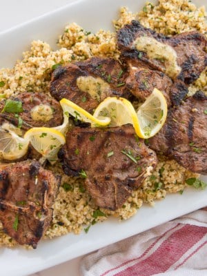 Garlic Herb Grilled Lamb Chops on a bed of farro garnished with twists of lemon.