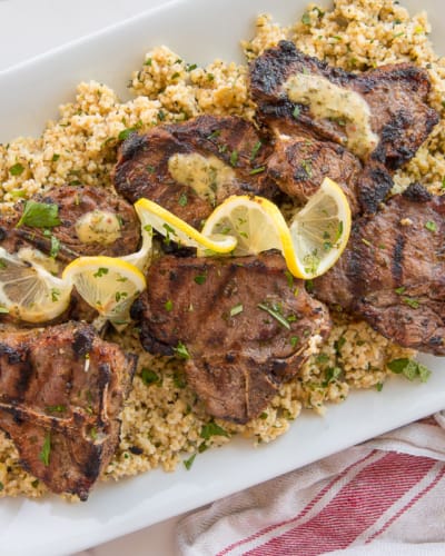 Garlic Herb Grilled Lamb Chops on a bed of farro garnished with twists of lemon.