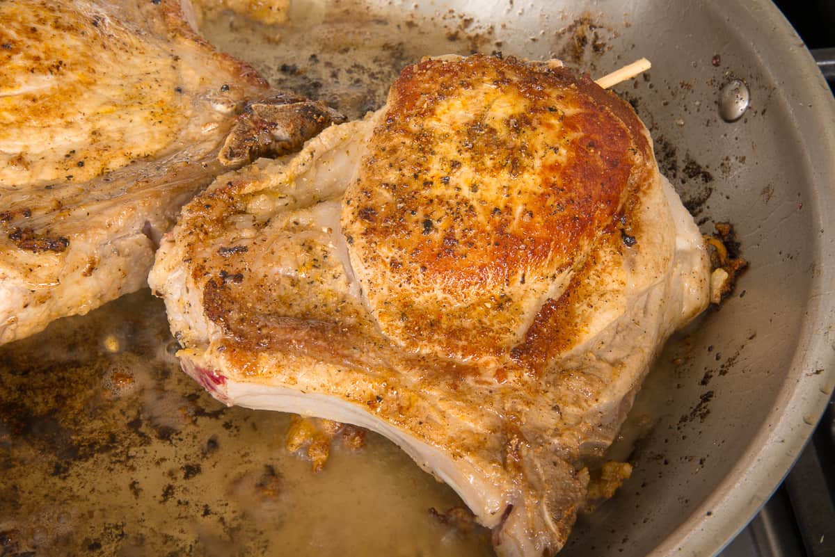 The stuffed pork chops are browned in a pan before going into the oven.