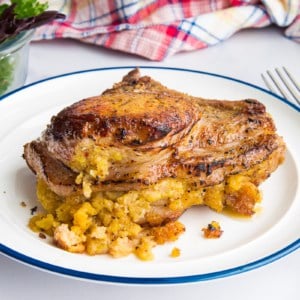 Pork Chops with Mofongo Stuffing on a white plate with a blue rim next to a fork and steak knife.