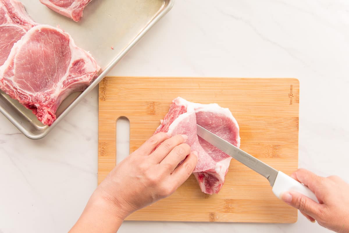 A hand uses a knife to cut a pocket into the meat.
