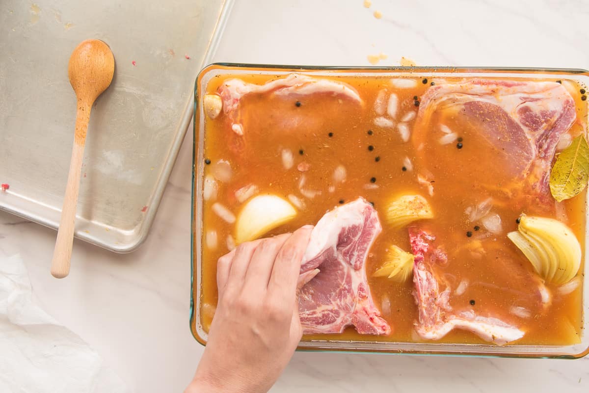 A hand places the last of the meat into a dish with the iced brine.